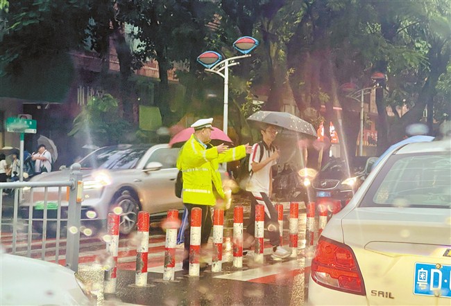 雨中坚守护学岗 温暖学生上学路